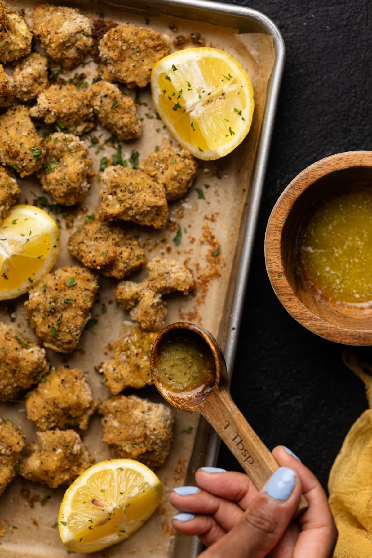 Lemon Pepper Cauliflower Bites on a baking sheet with lemon butter poured on top.