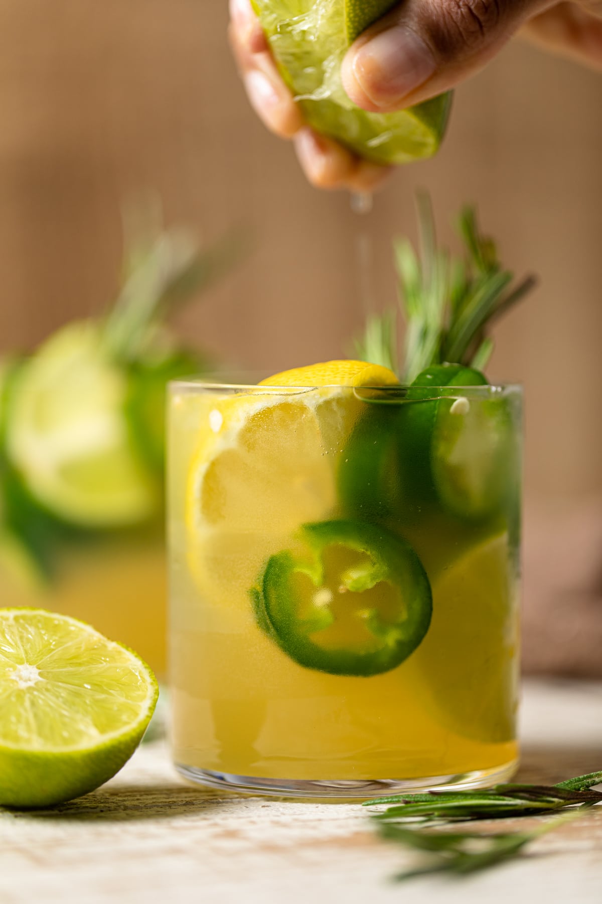 Person squeezing a citrus fruit into a Jalapeno Lemon-Lime Mocktail.