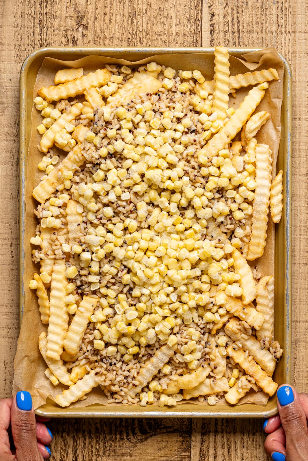 French fries on a sheet pan with corn and quinoa topping.