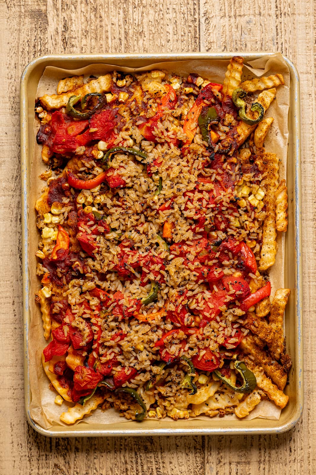 Fries on sheet pan with all toppings including seasonings.