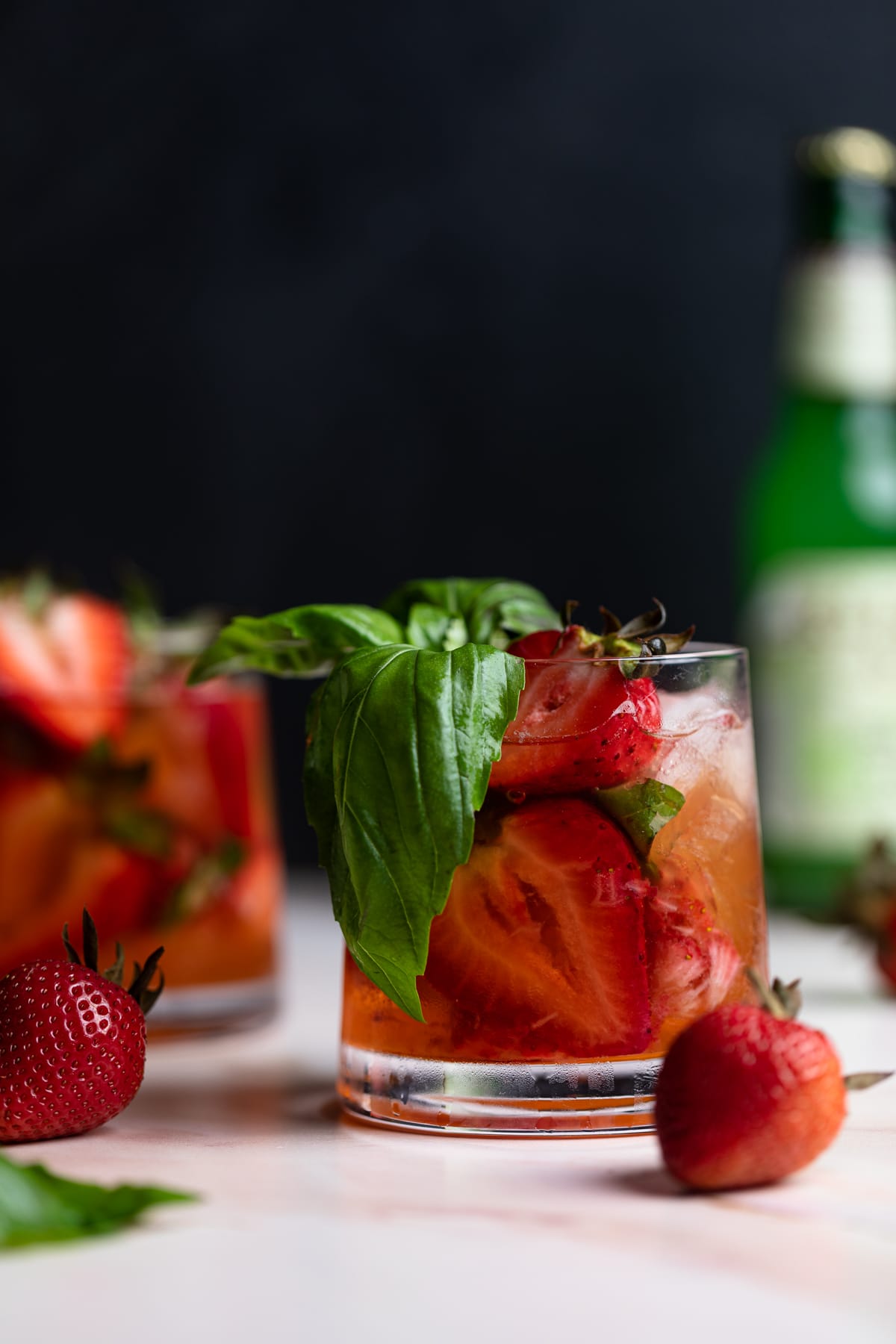 Strawberry Basil Pineapple Mocktail in a glass with fresh strawberries and basil.