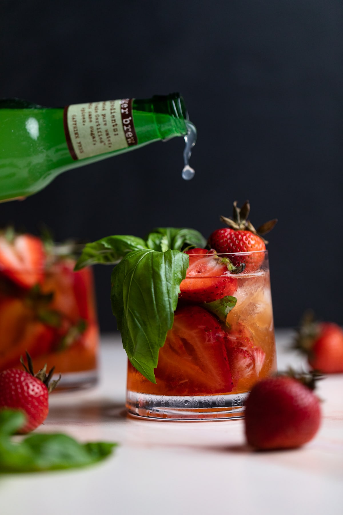 Ginger beer pouring into a Strawberry Basil Pineapple Mocktail.