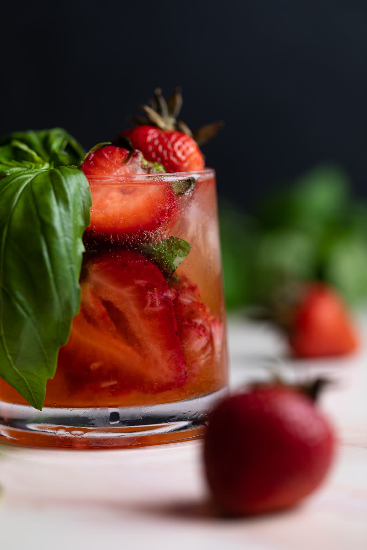 Strawberry Basil Pineapple Mocktail in a small glass with fresh strawberries and basil.