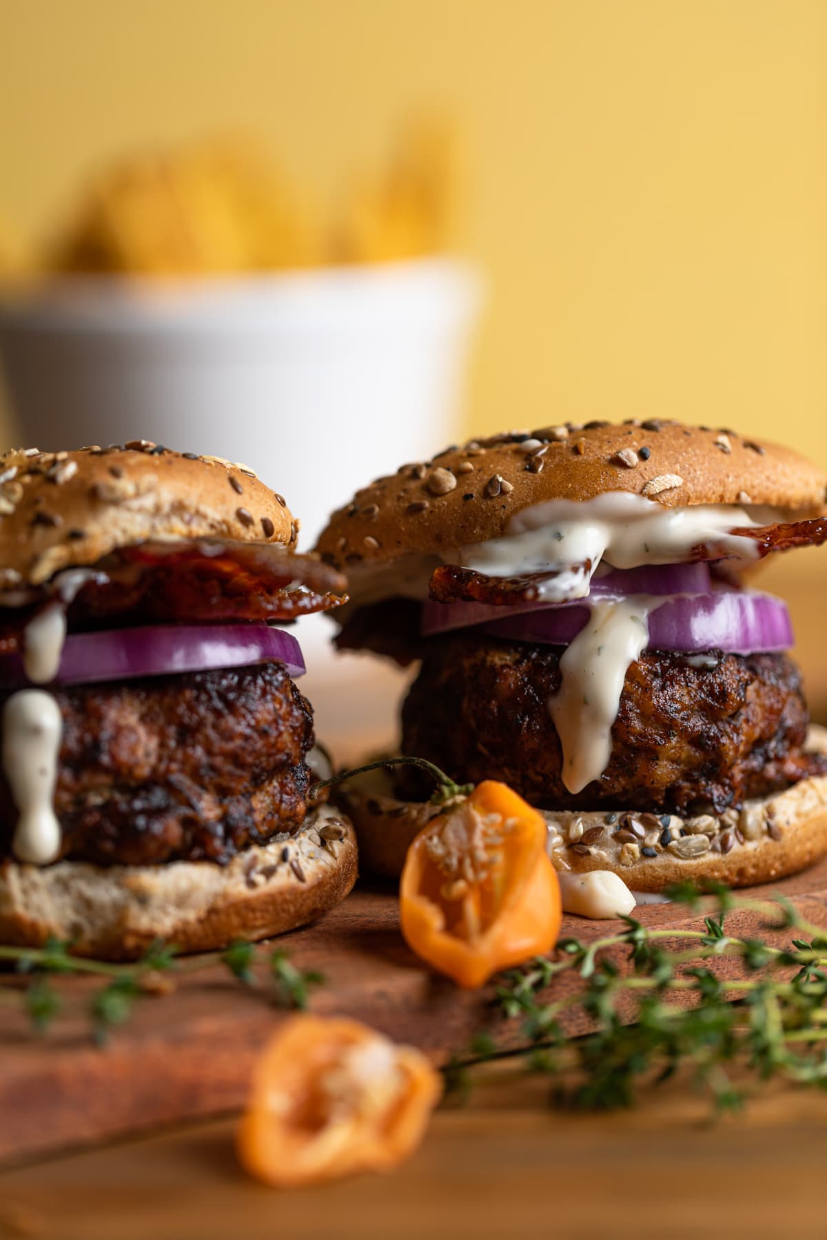 Two barbeque Jerk Bacon Turkey Burgers on a wooden board.