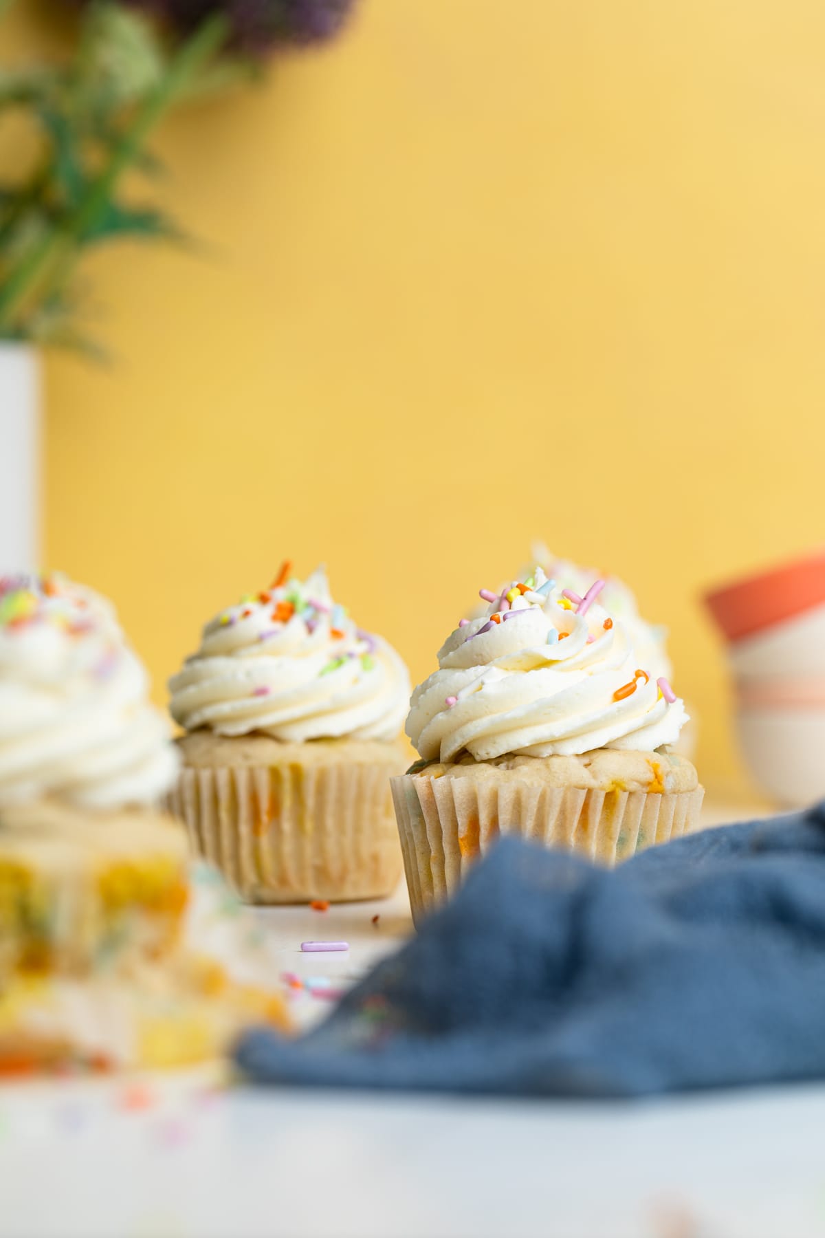 Vegan Funfetti Cupcakes on a table with a blue cloth napkin.