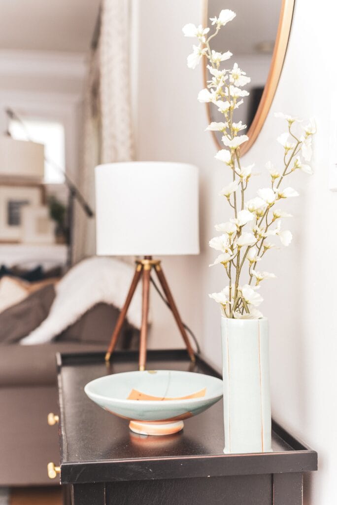 White flowers in a tall, white vase on a small table.