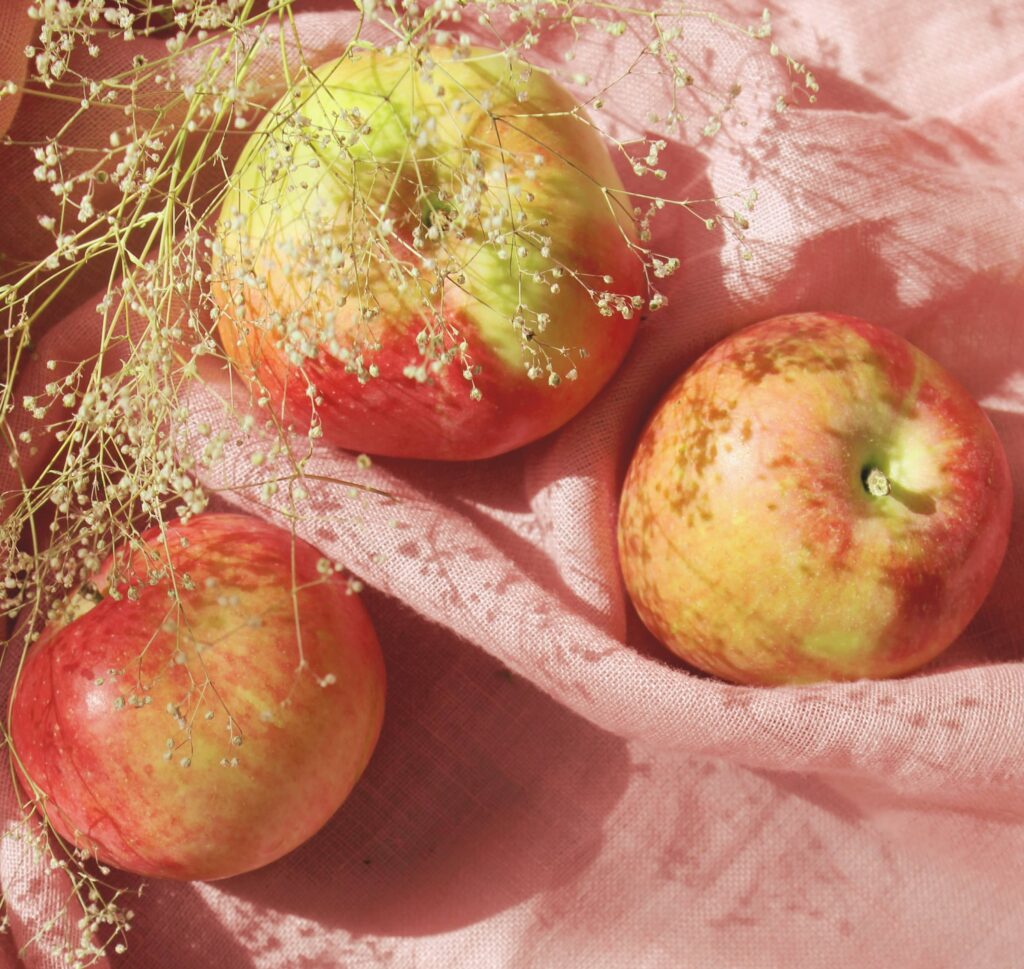 Apples on a pink cloth napkin.