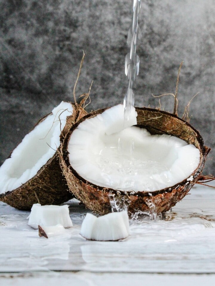 Water pouring over a halved coconut.