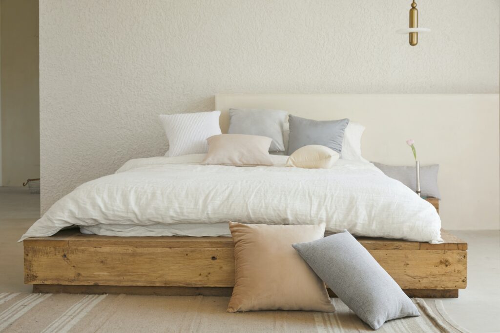 Pastel pillows on and around a white bed.