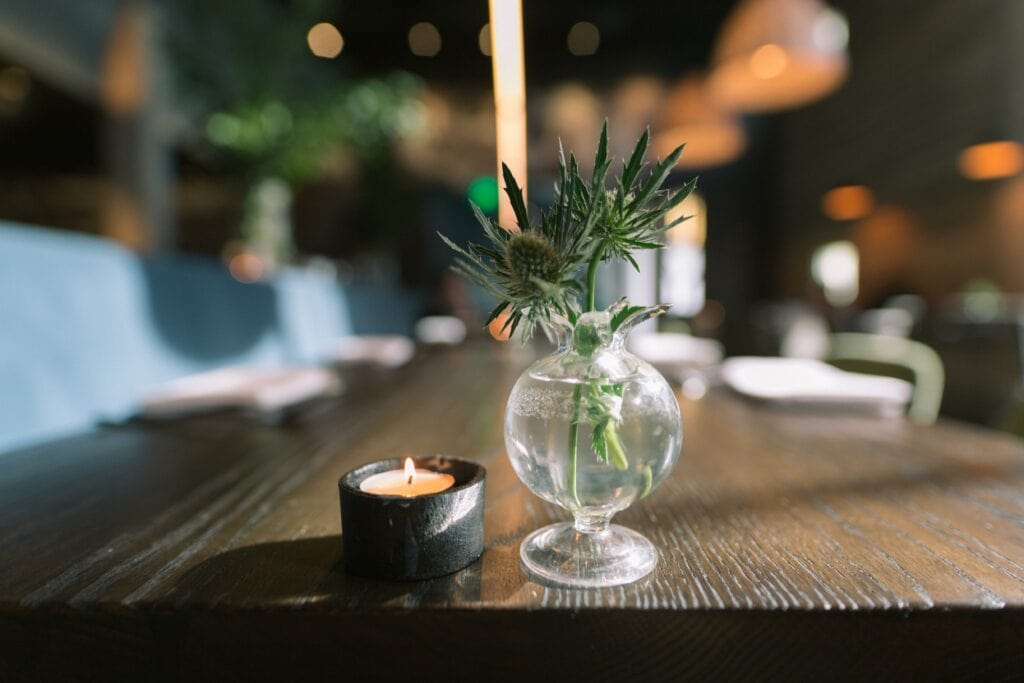 Candle and a clear vase on a dark wooden table.