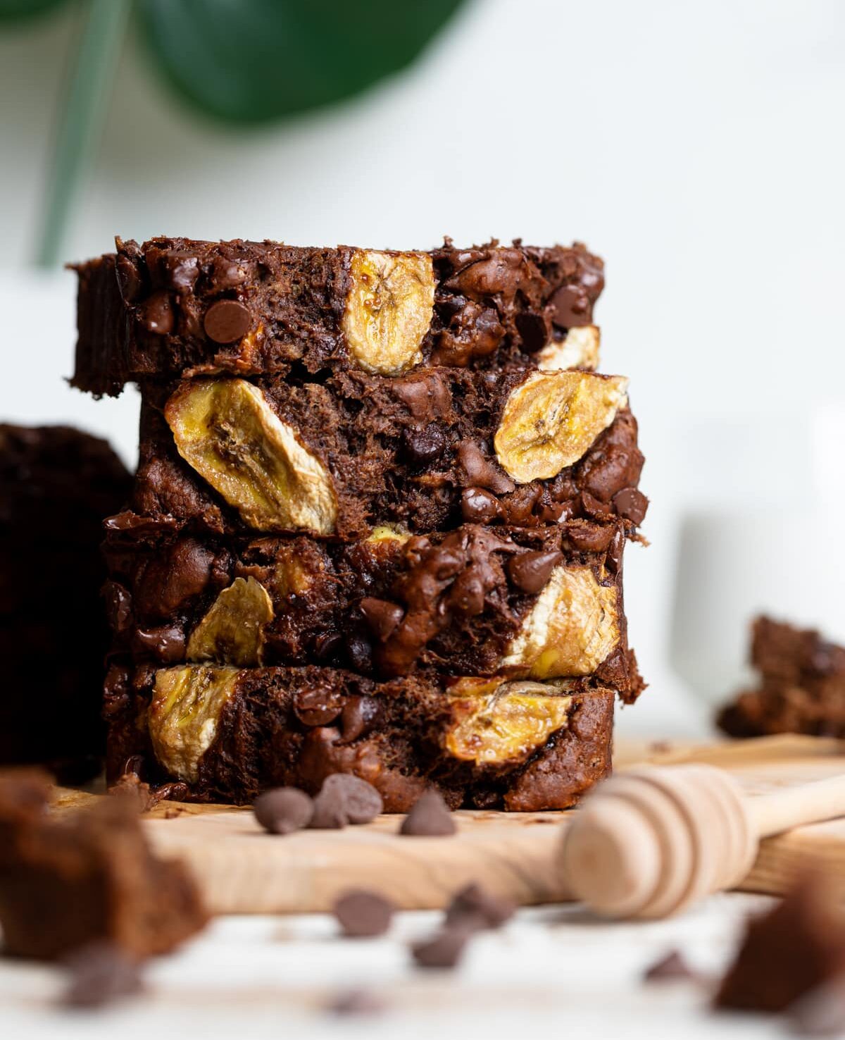 Slices of Vegan Chocolate Bourbon Banana Bread stacked on a wooden board.