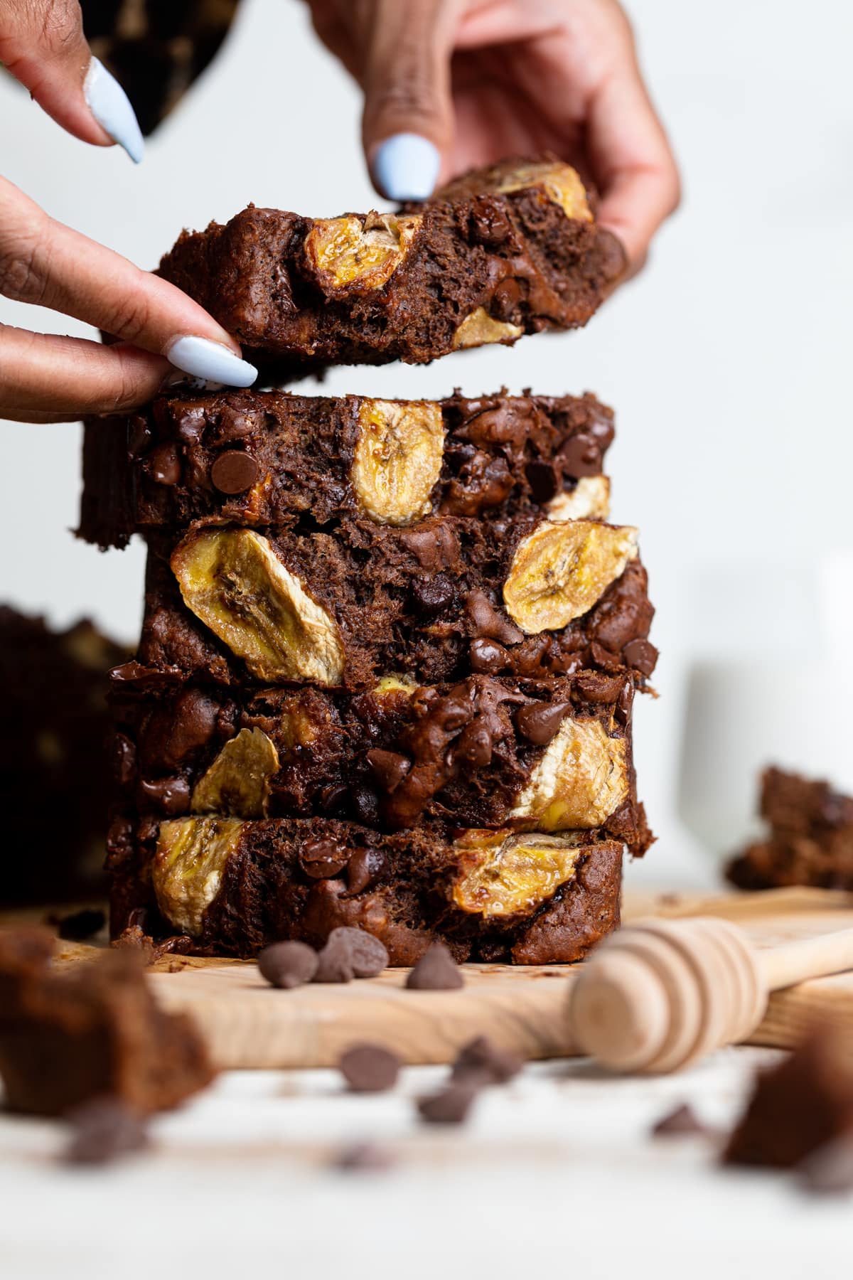 Person stacking slices of Vegan Chocolate Bourbon Banana Bread.