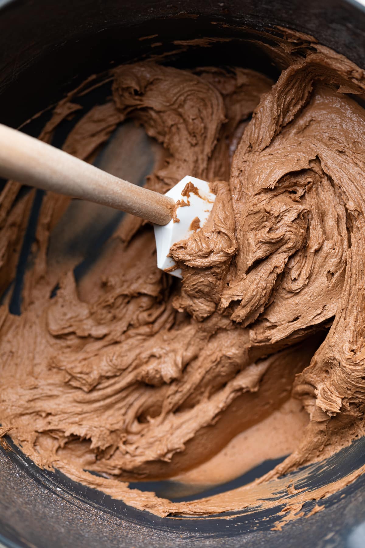 Spatula in a bowl of chocolate frosting.