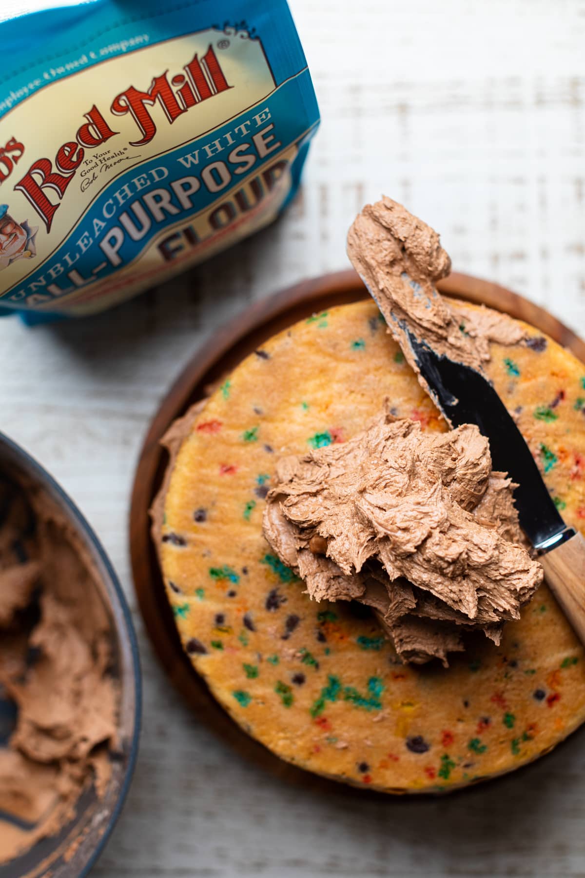 Chocolate frosting piled on a Confetti Chocolate Chip Cake.