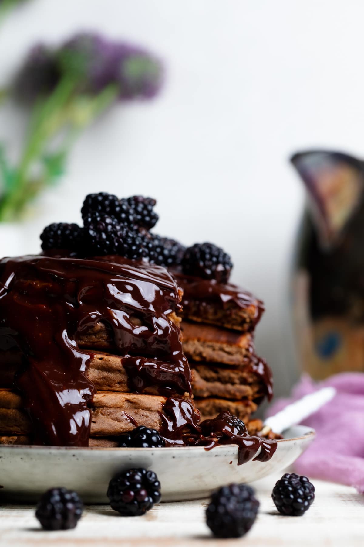 Vegan Chocolate Pancakes stacked on a plate with Blackberries.