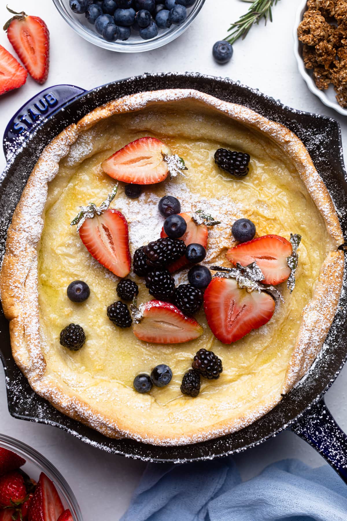 Berries atop a Dutch Baby Pancake in a skillet.