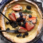 Fork and knife on a Dutch Baby Pancake with Berries.