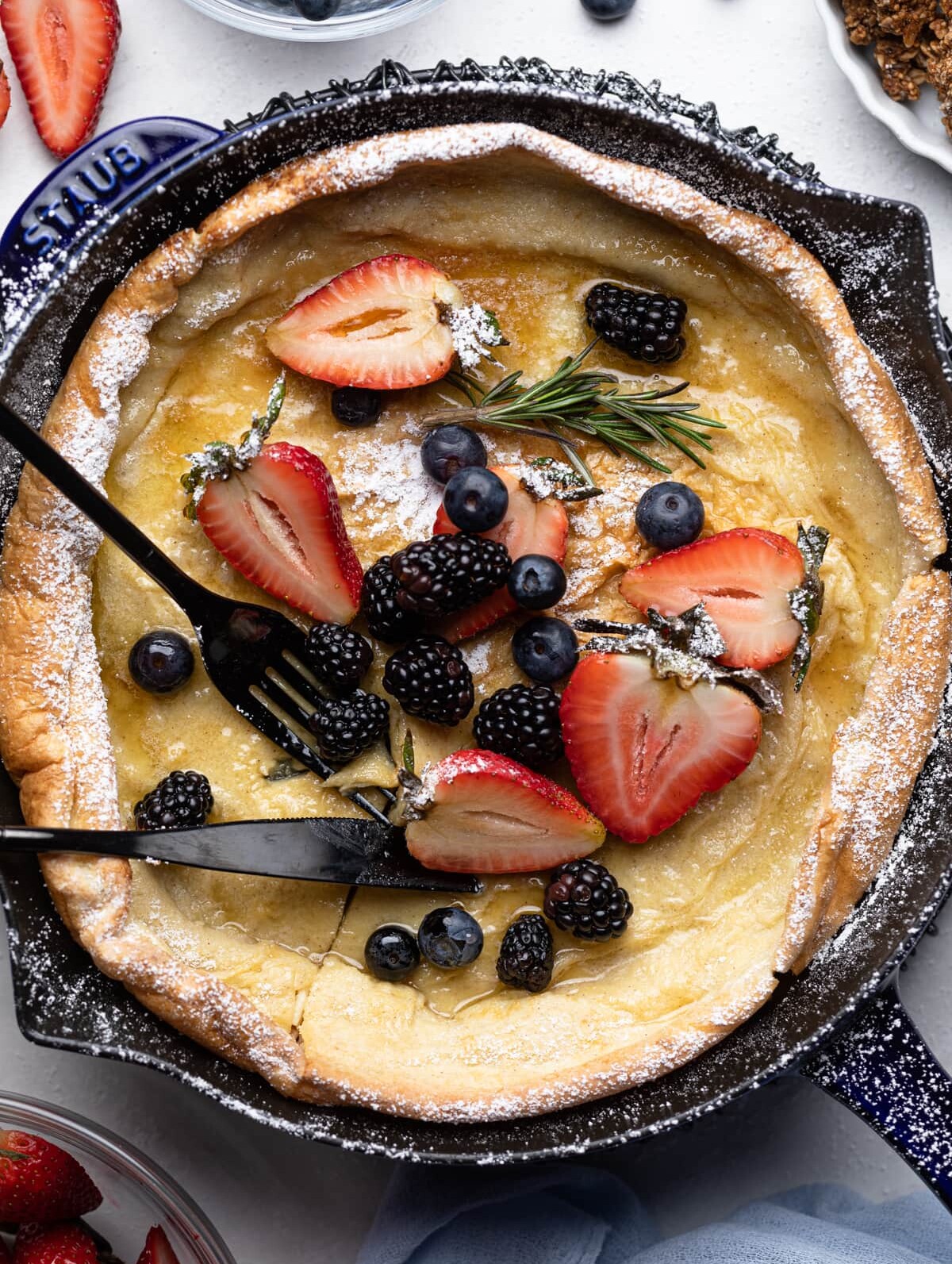 Fork and knife on a Dutch Baby Pancake with Berries.