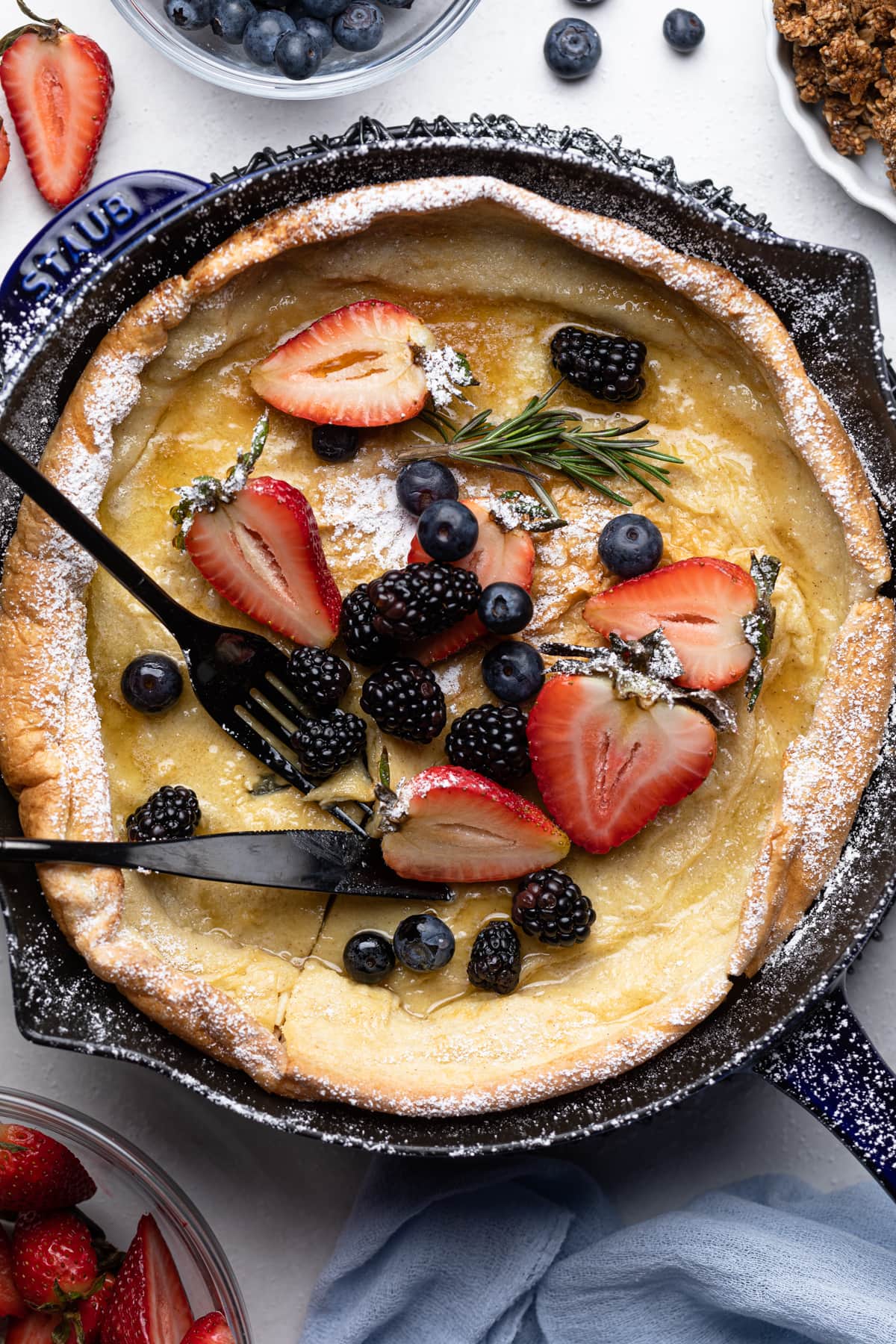 Fork and knife on a Dutch Baby Pancake with Berries.