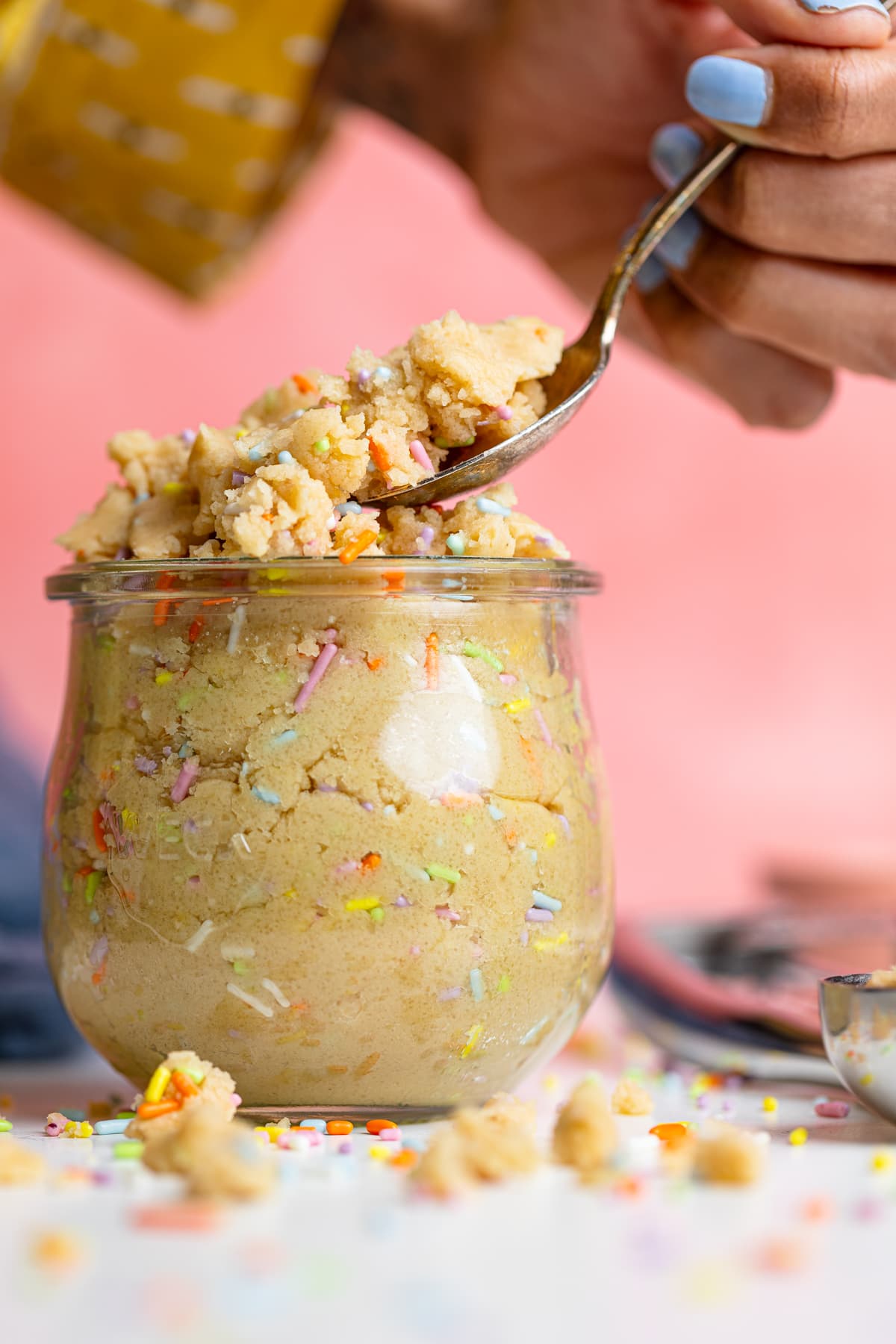 Woman using a spoon to scoop Edible Vegan Funfetti Cookie Dough.