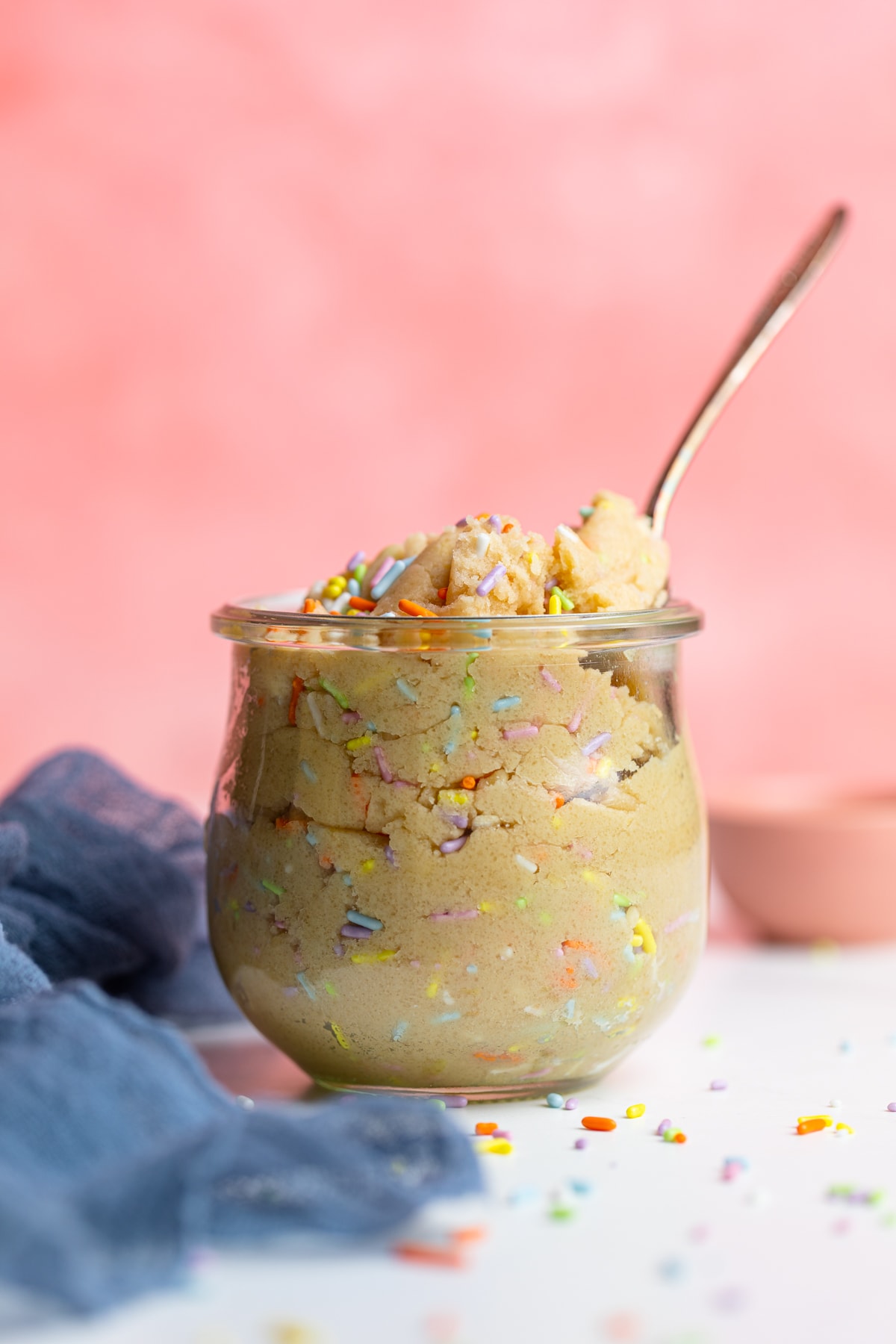 Spoon scooping Edible Vegan Funfetti Cookie Dough from a glass.