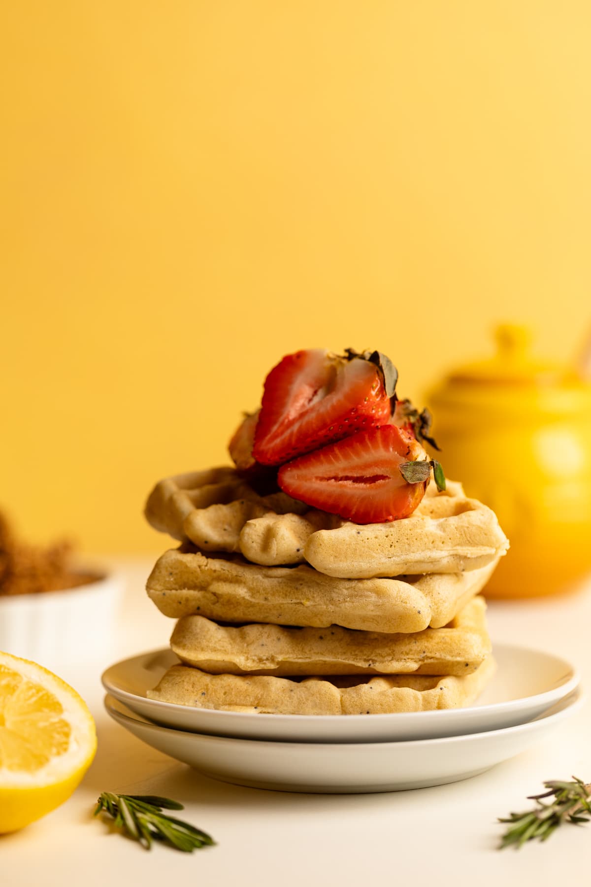 Stack of Gluten-Free Lemon Poppyseed Waffles topped with halved-strawberries