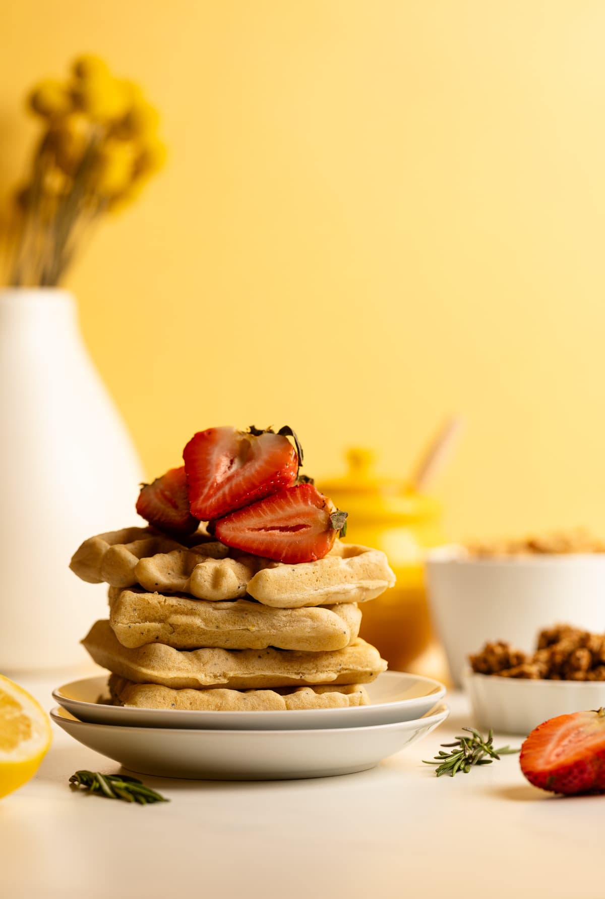 Sliced strawberries atop a stack of Gluten-Free Lemon Poppyseed Waffles.