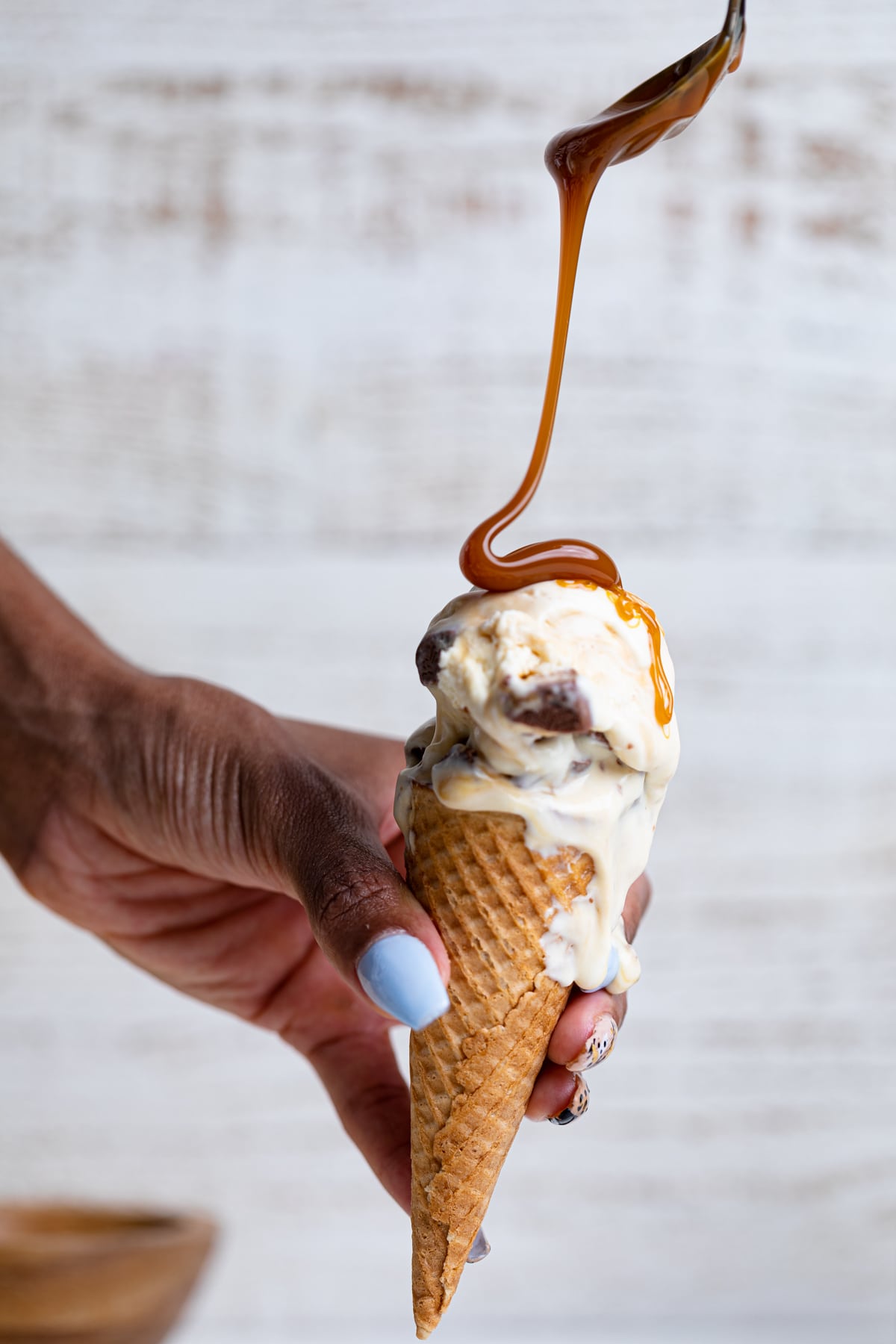 Caramel drizzling onto a Loaded No-Churn Snickers Ice Cream cone.