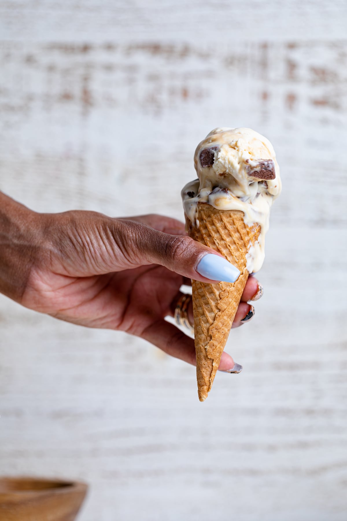 Woman holding a Loaded No-Churn Snickers Ice Cream ice cream cone.