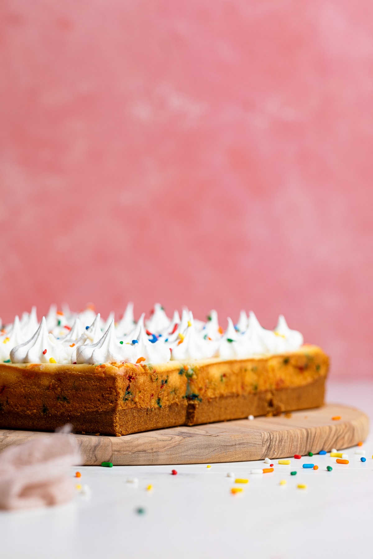 Cut Funfetti Cheesecake Bars on a wooden board.