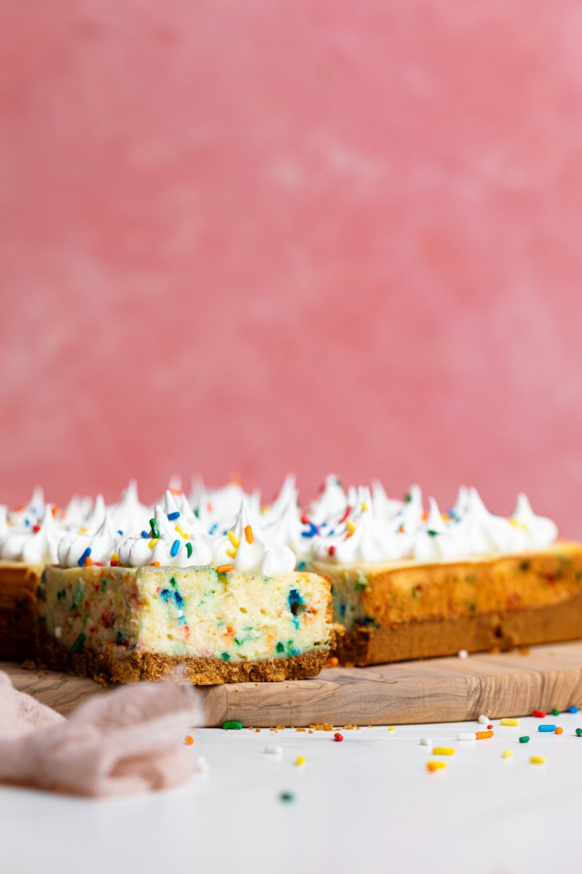 Funfetti Cheesecake Bars on a wooden board.