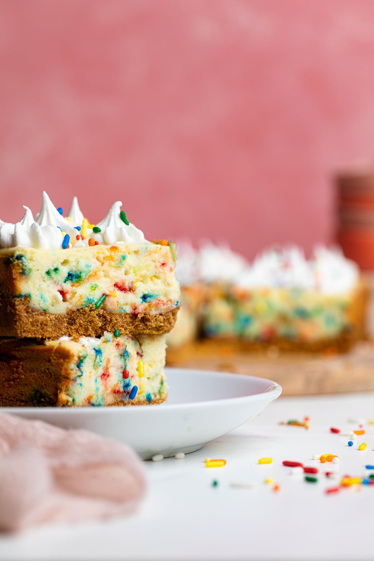Stack of Funfetti Cheesecake Bars on a white plate.