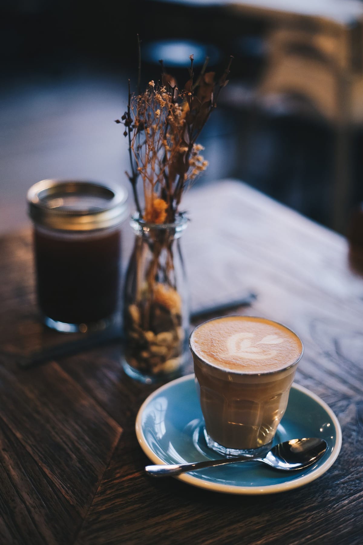 Cup of coffee on a blue plate with a spoon.