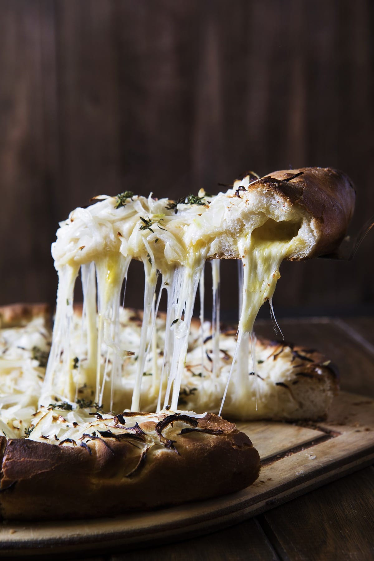 Spatula lifting a slice of cheesy bread .