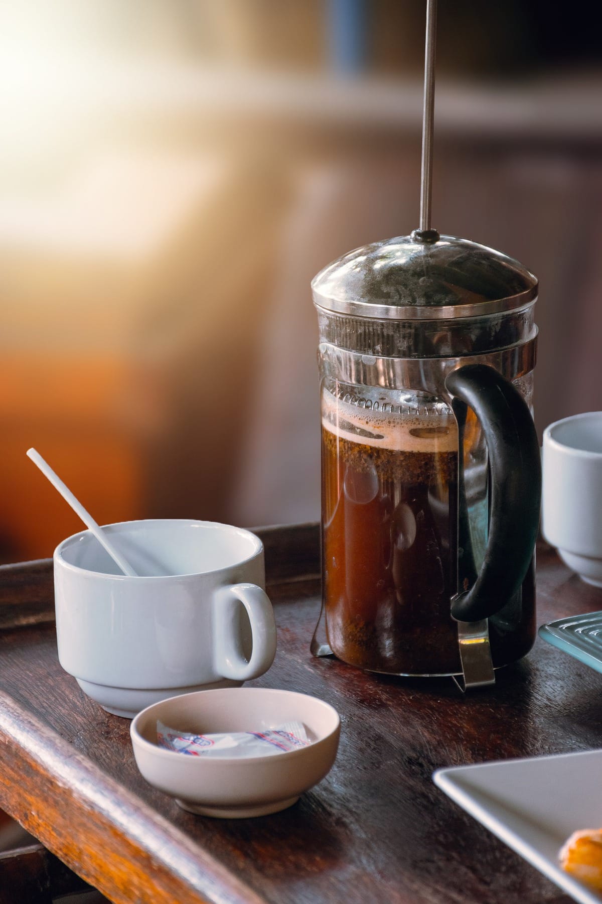 White mug next to a French press coffee maker.