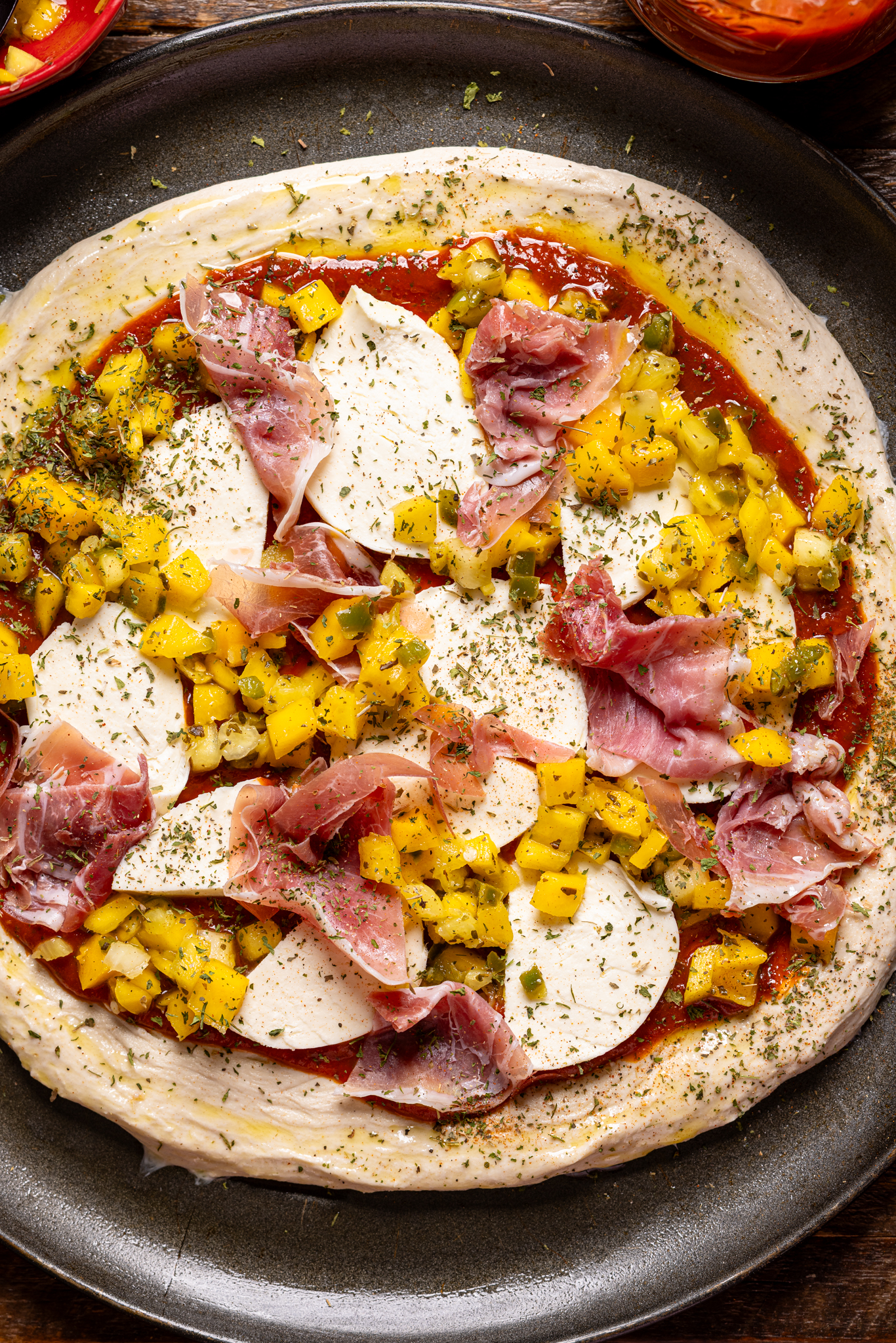 Image of ingredients and seasonings on Hawaiian pizza ready to be baked.