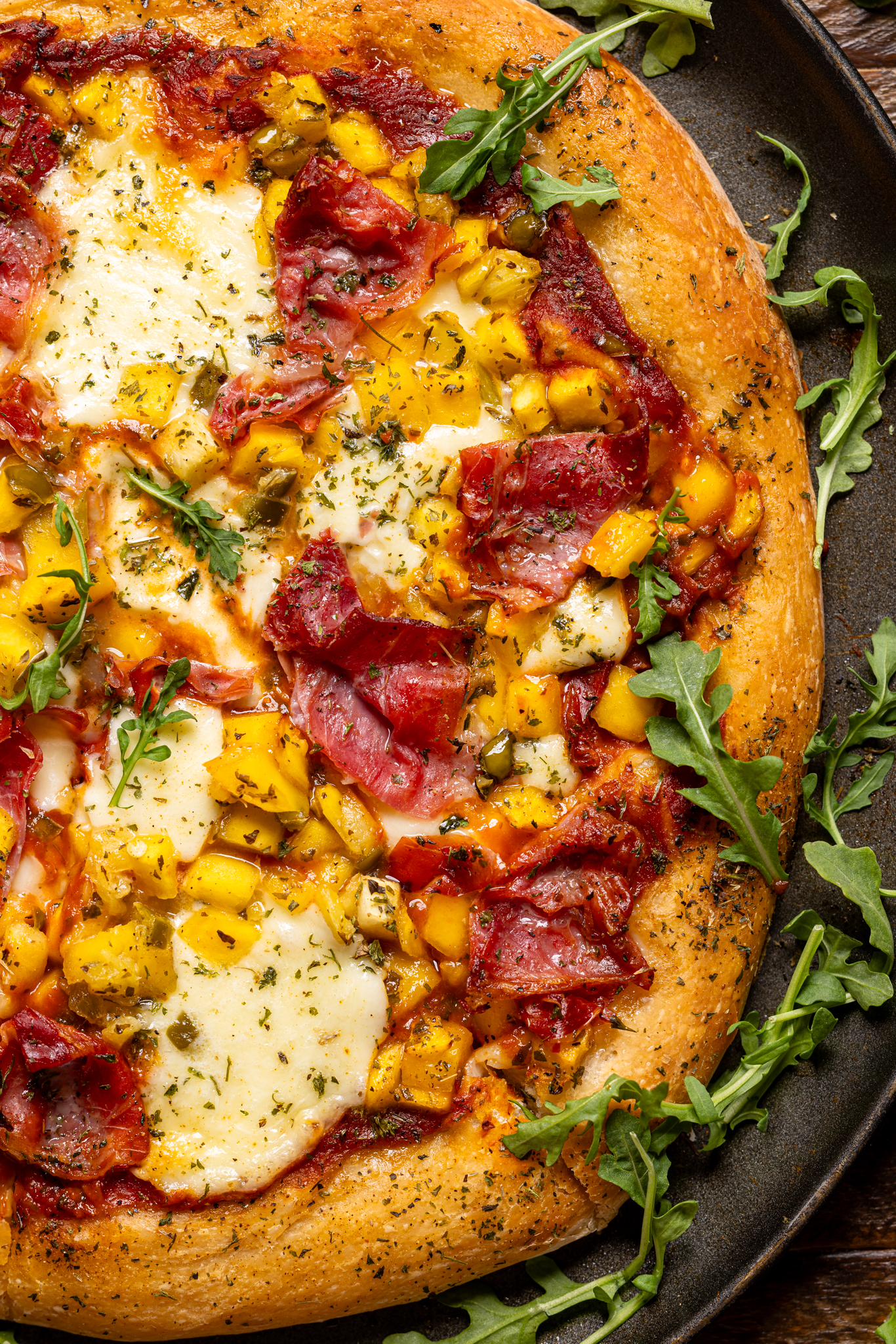 Up close shot of Hawaiian pizza on a grey pan.