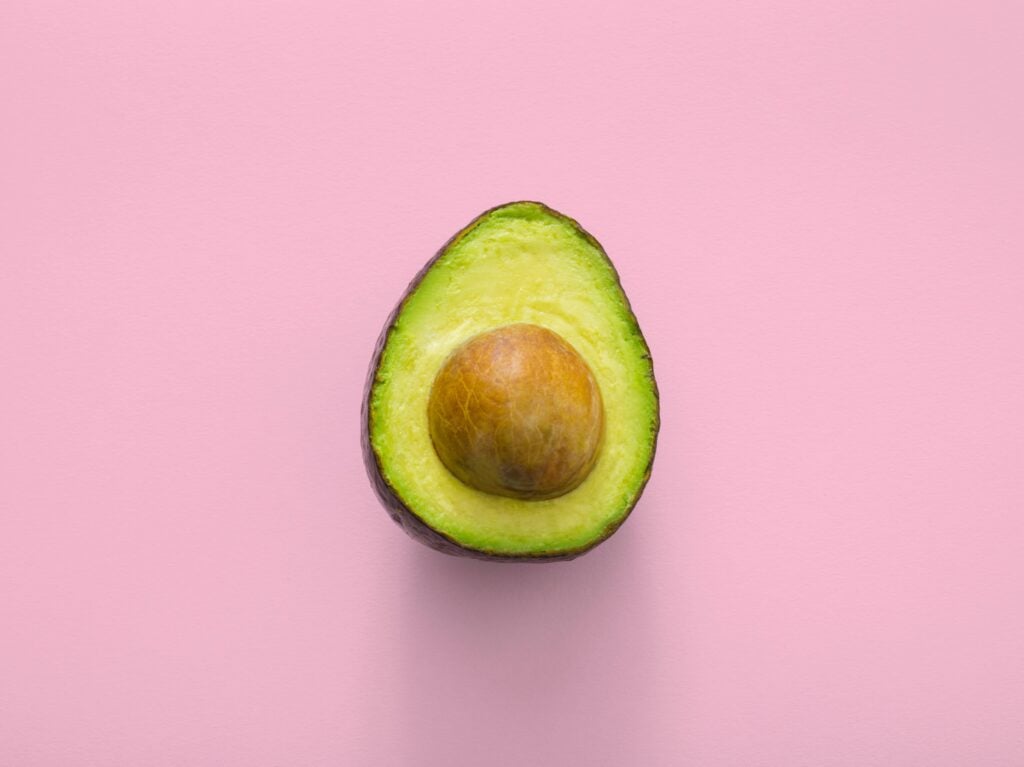 Avocado half against a pink background