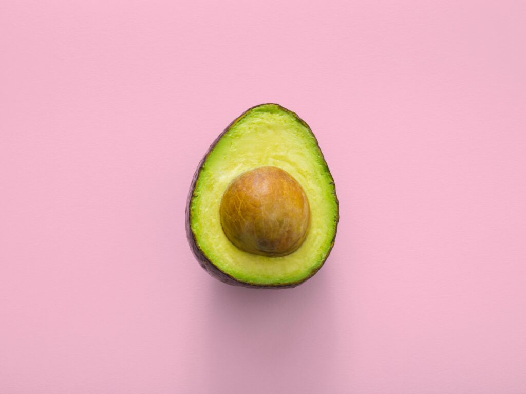 Avocado half against a pink background