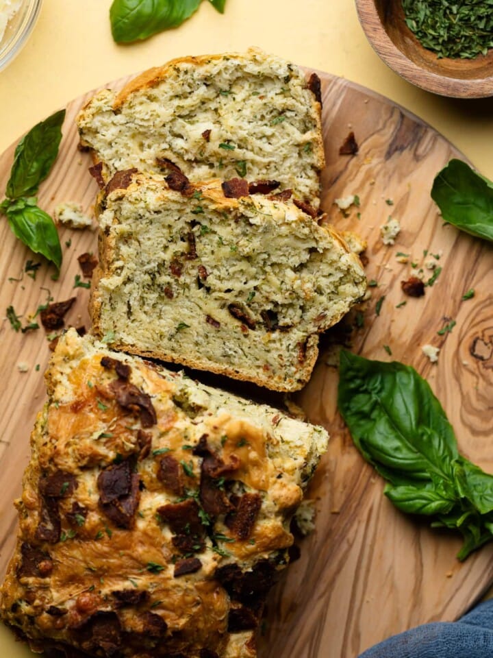 Loaded Cheddar Pesto Zucchini Bread with Bacon sliced on a wooden board.