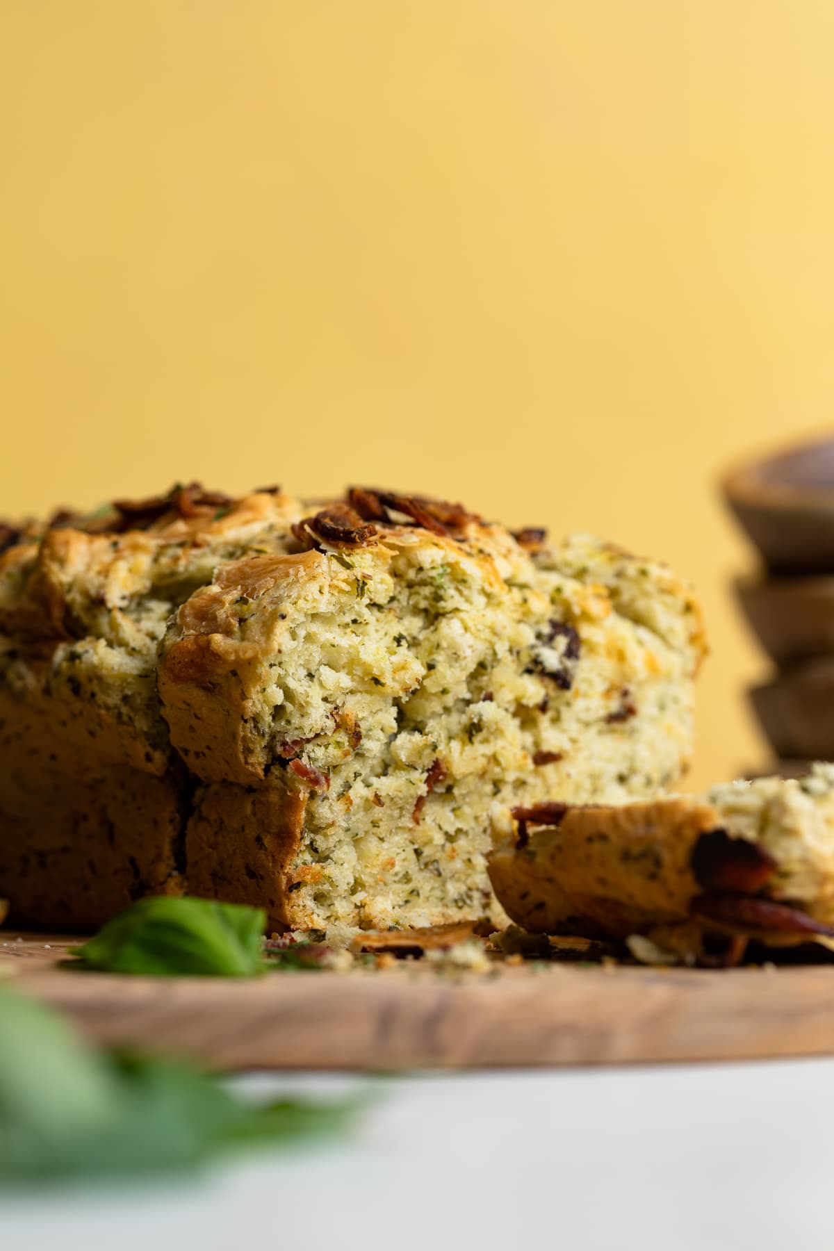 Partially-sliced loaf of Loaded Cheddar Pesto Zucchini Bread with Bacon.