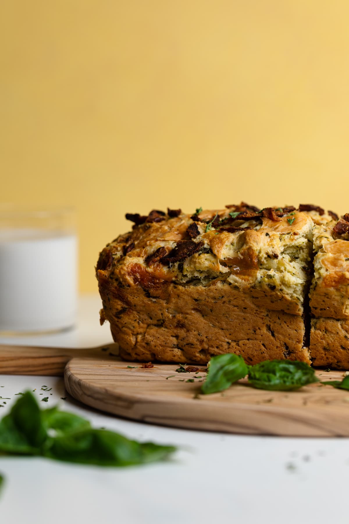 Loaf of Loaded Cheddar Pesto Zucchini Bread with Bacon on wooden board.