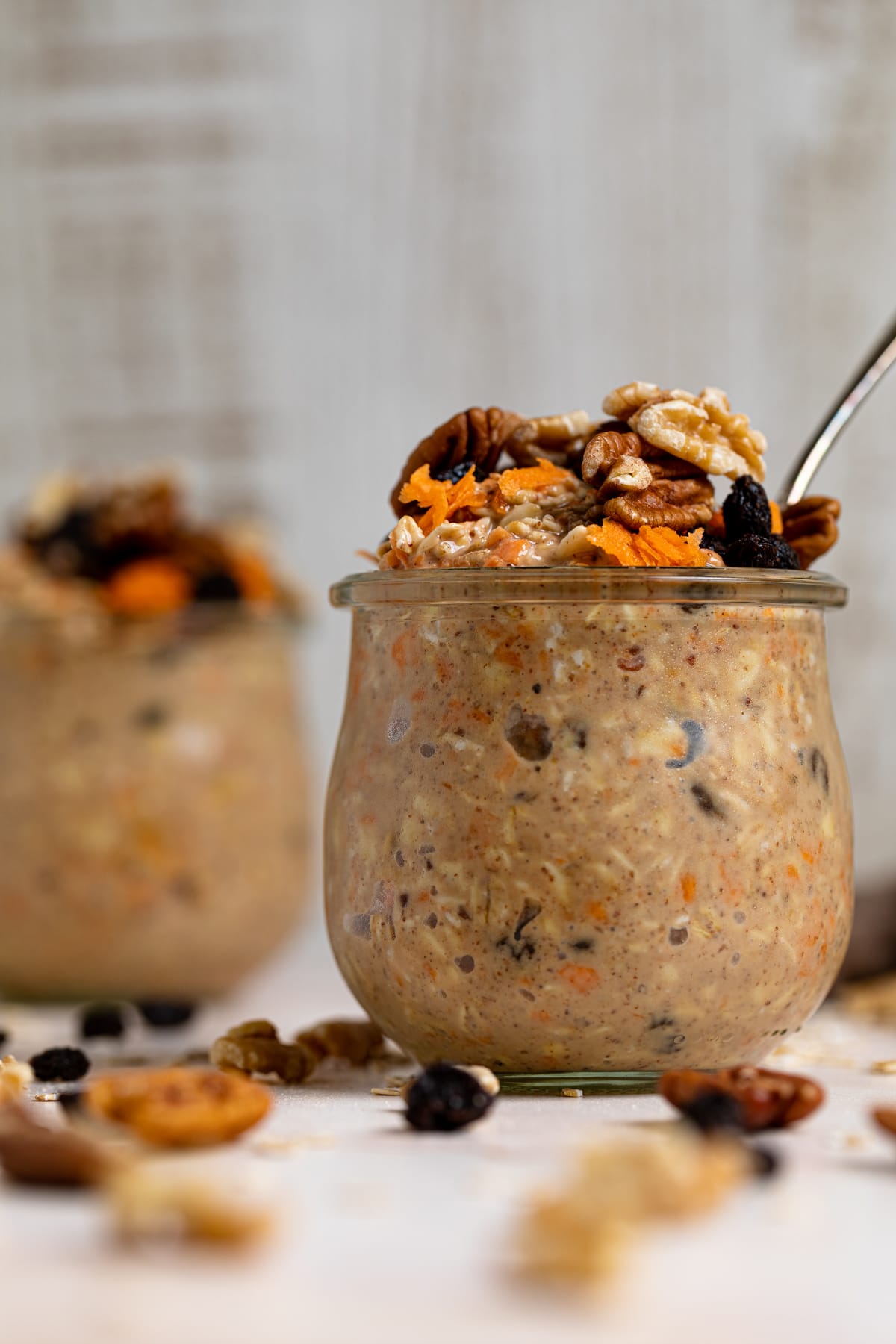 Closeup of a glass of Spiced Carrot Cake Overnight Oats with a spoon