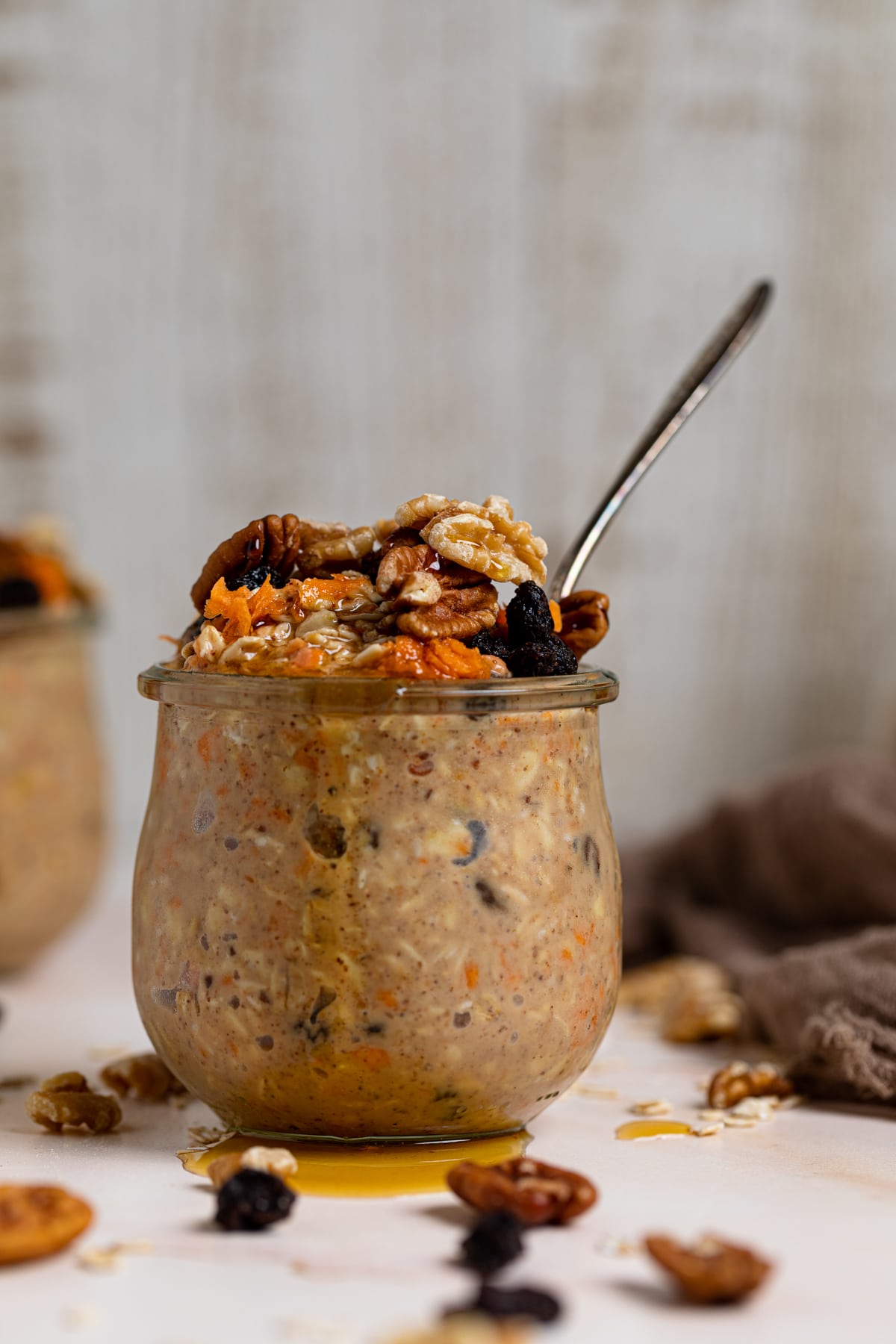 Spiced Carrot Cake Overnight Oats with maple syrup dripping over the side
