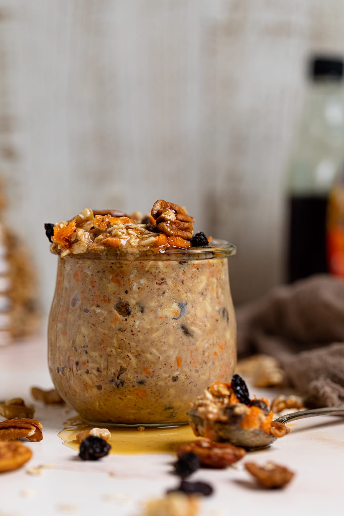 Spoon of Spiced Carrot Cake Overnight Oats next to the glass full of the oats