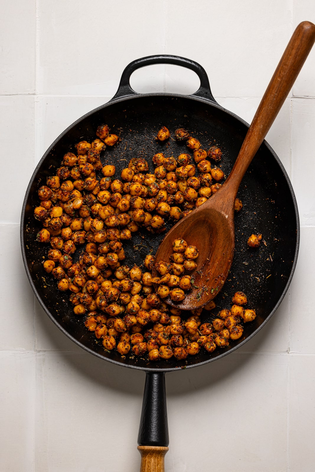 Sauteed chickpeas in a skillet with wooden spoon.