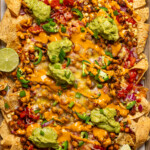 Nachos with all toppings baked and on a wood board.