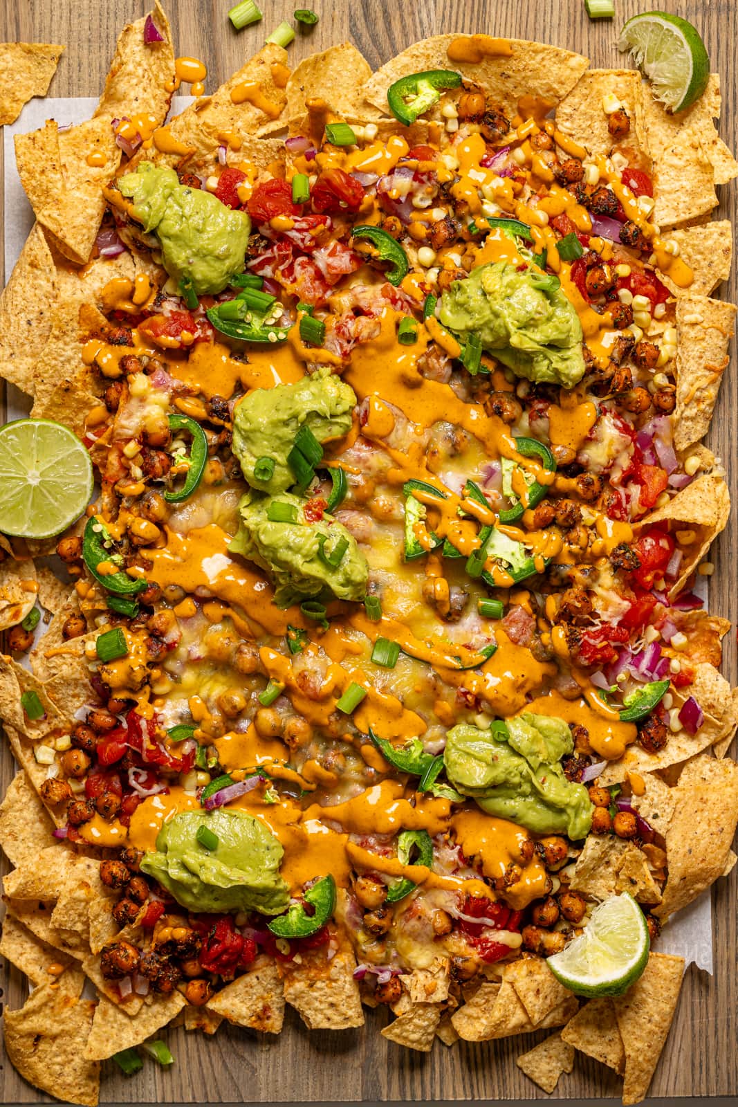 Nachos with all toppings baked and on a wood board.