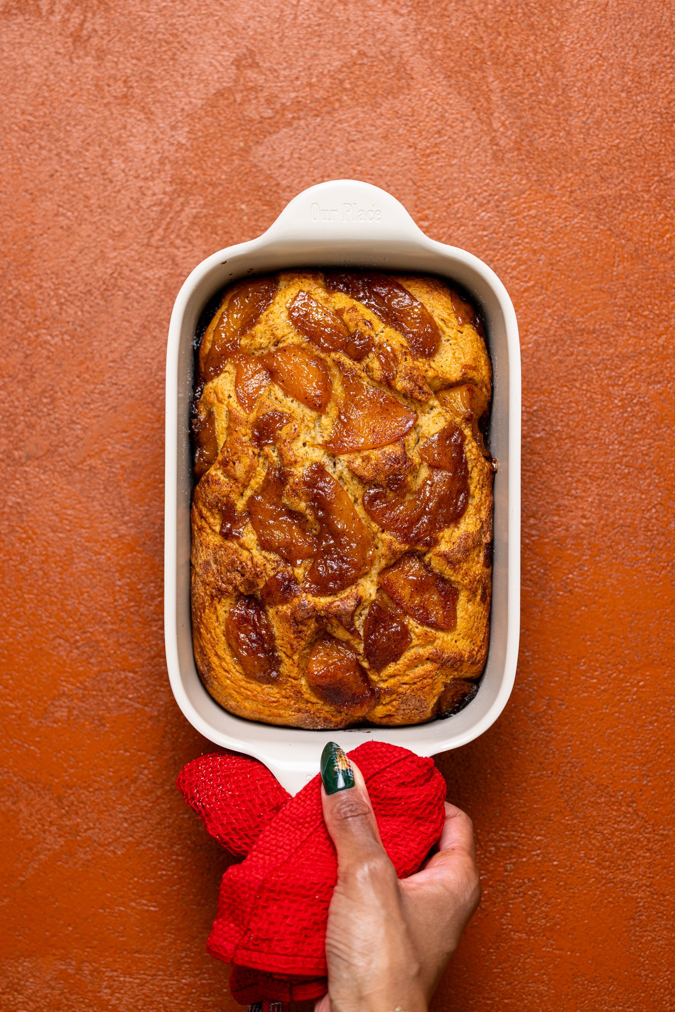 Baked Easy Homemade Cinnamon Peach Bread in a bread pan being held by woman hand.