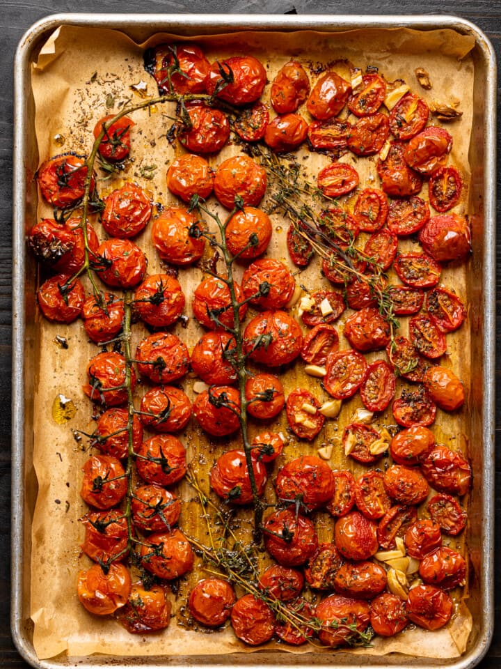 Roasted tomatoes on a baking sheet lined with parchment paper.